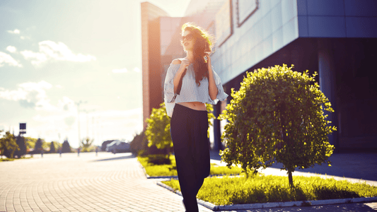 Fit female walking home after her day at work. It is sunny and she looks happy to be outside.